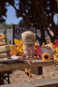 A tiramisu latte with a plate of tiramisu surrounded by autumnal decor.