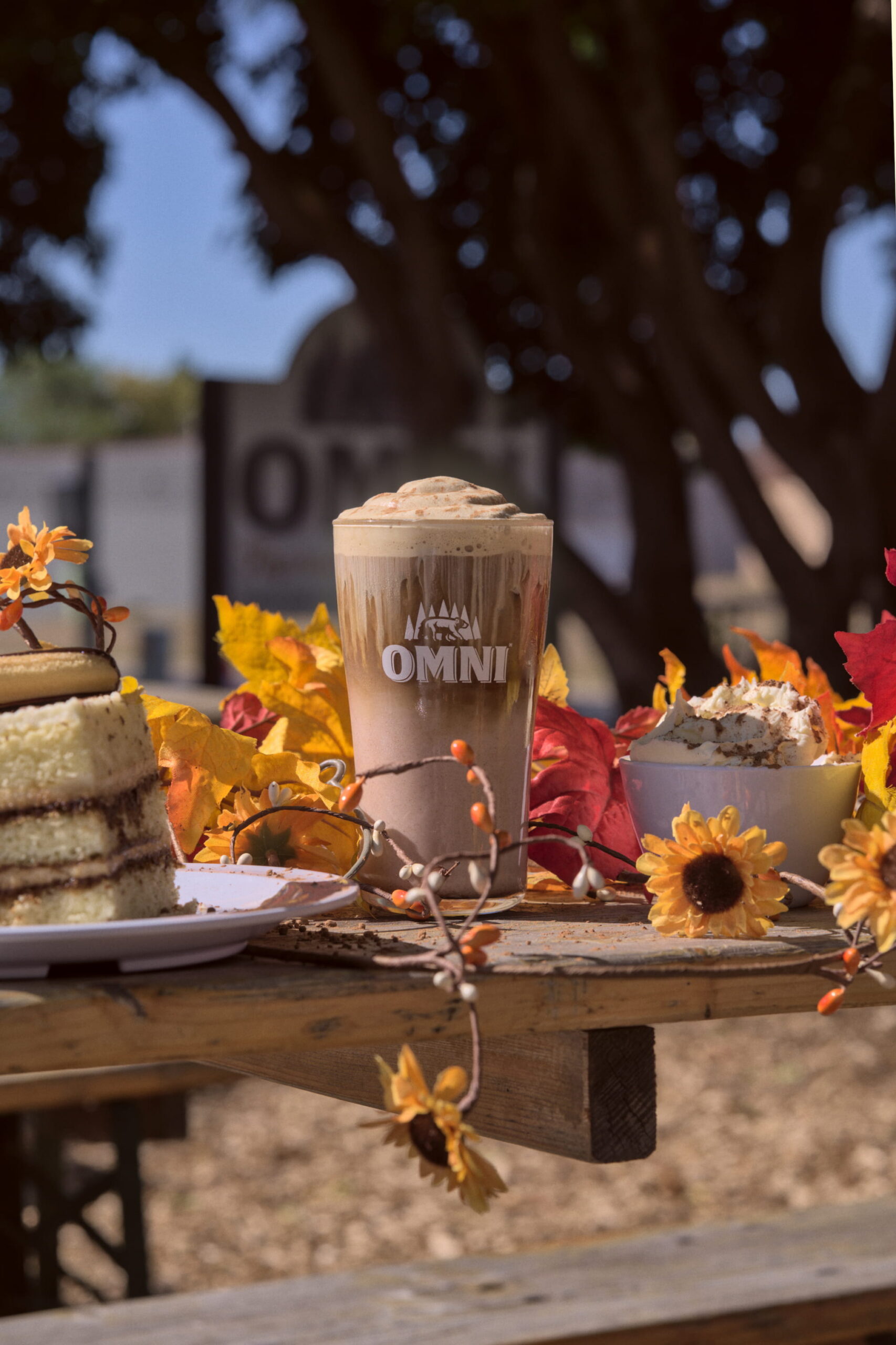 A tiramisu latte with a plate of tiramisu surrounded by autumnal decor.